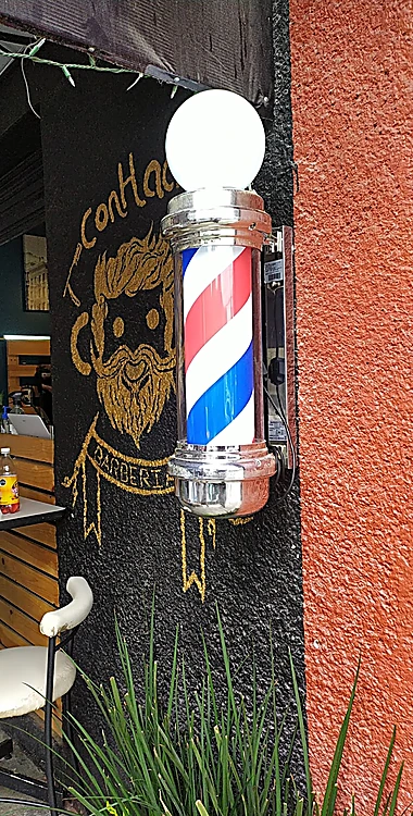 Entrada con poste de barbero, mural dorado de ConHache y muro naranja