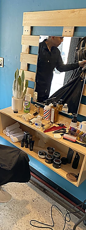 Repisa de pino con productos para cabello y barba frente al espejo